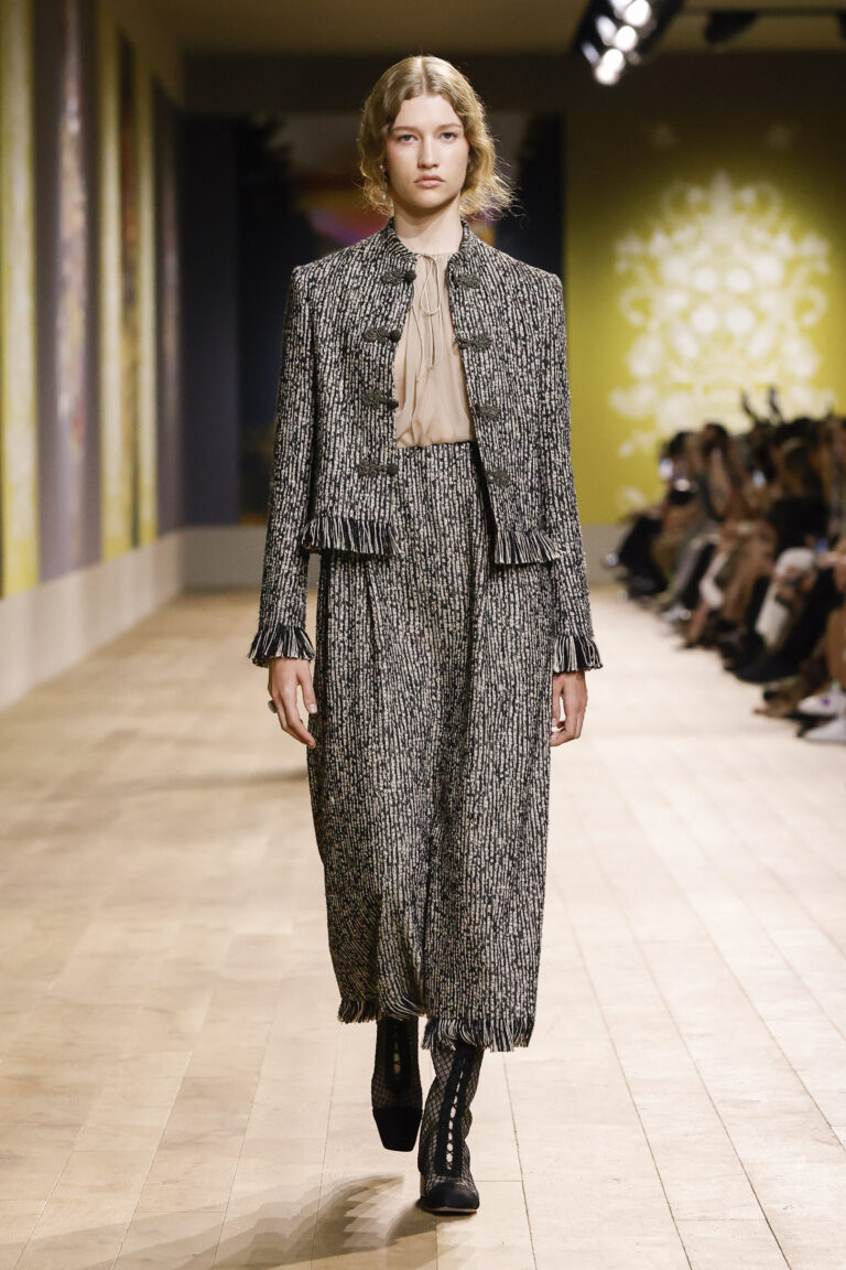 Block and ochre tweed set, jacket and skirt with frayed edges enhanced by brandebourgs. Shirt in beige silk chiffon.