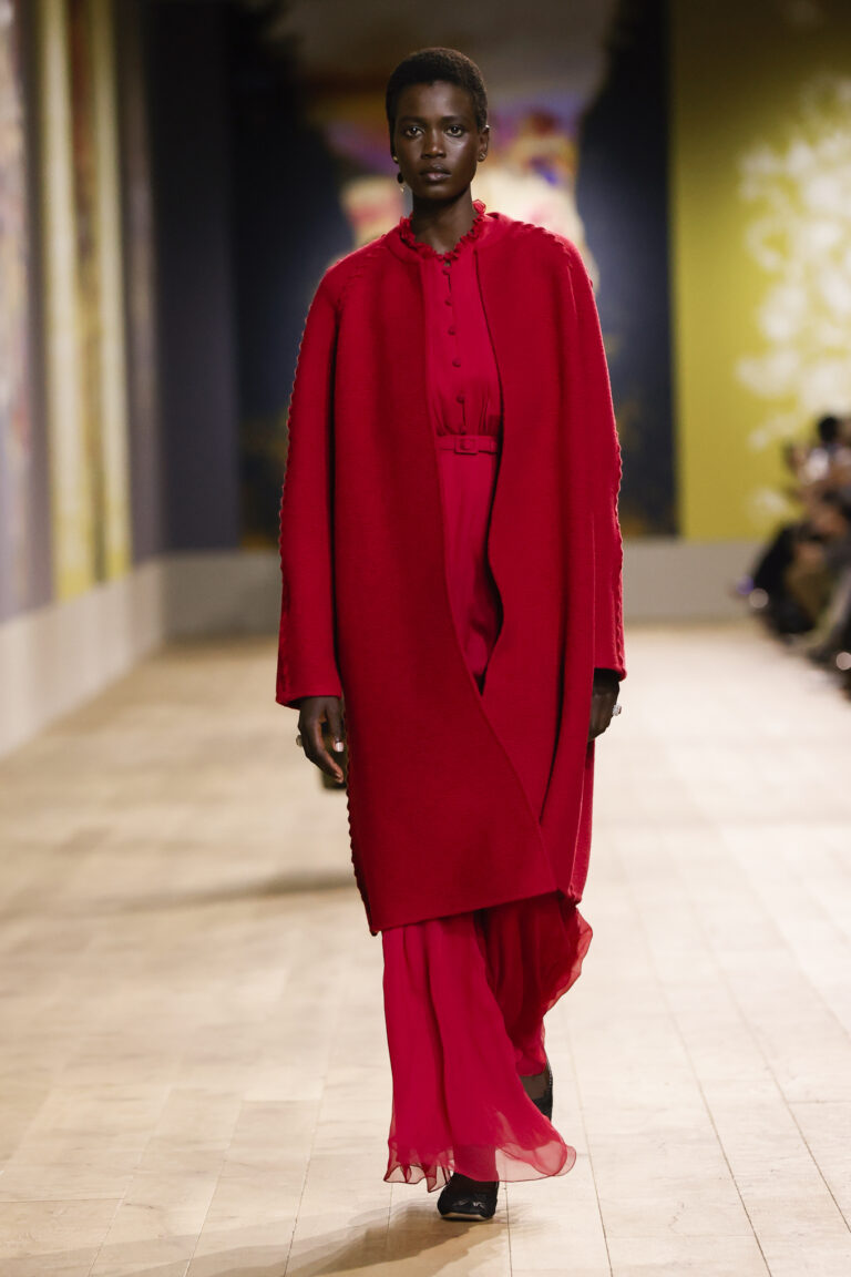 Red cashmere coat highlighted with silk lacing over a red silk chiffon set with small embroidered buttons.